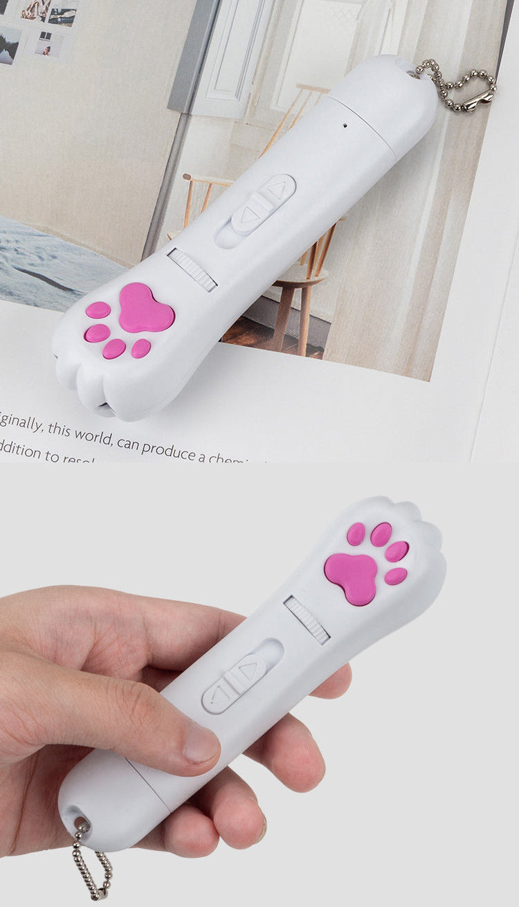 White PawBeam laser cat toy remote control with pink paw prints held by a hand on a light background