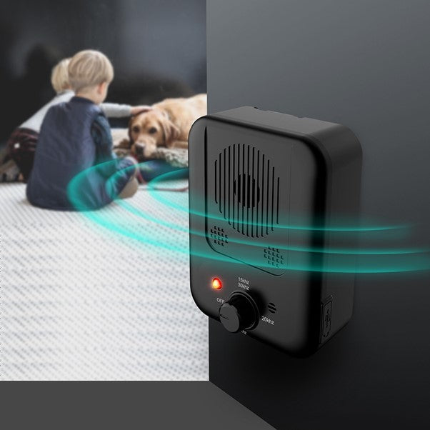 Dog sitting calmly with children near BarkLogic bark control unit in hallway

